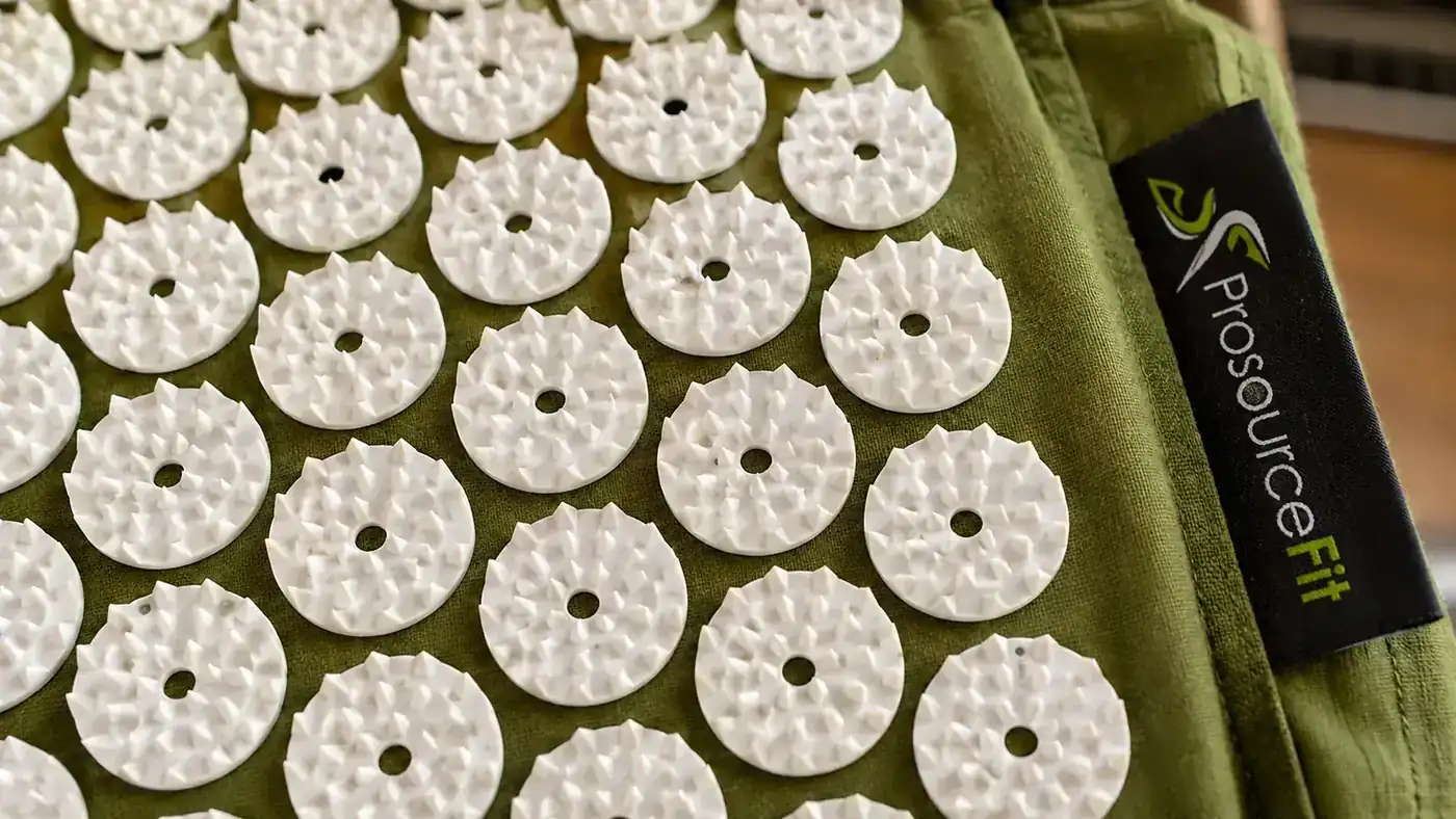 Close-up of an acupressure mat's plastic spike tiles showing a couple of small worn or missing points after weeks of use