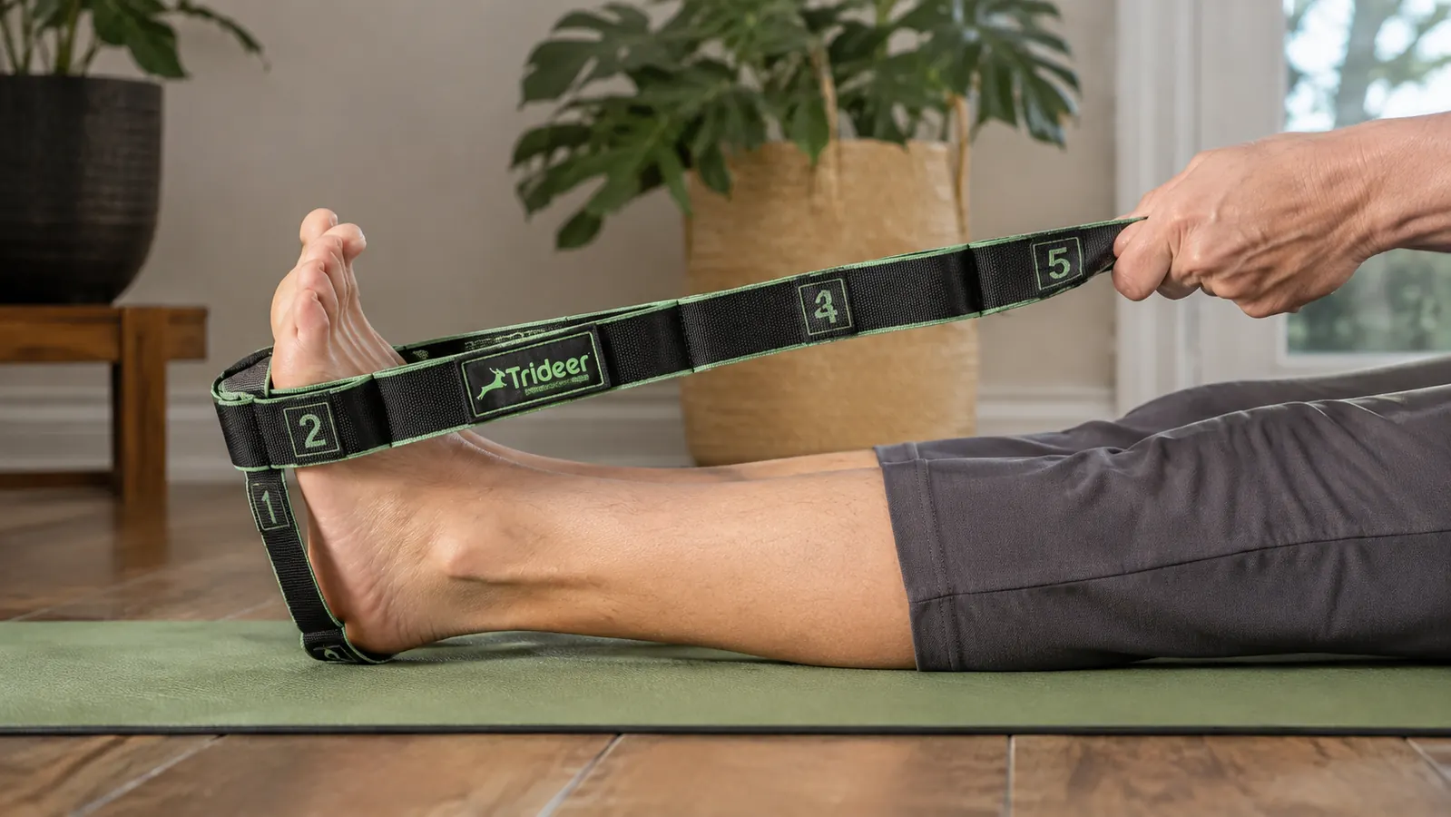 Close-up of a hand pulling a numbered loop on a stretching strap wrapped around a foot during a hamstring stretch