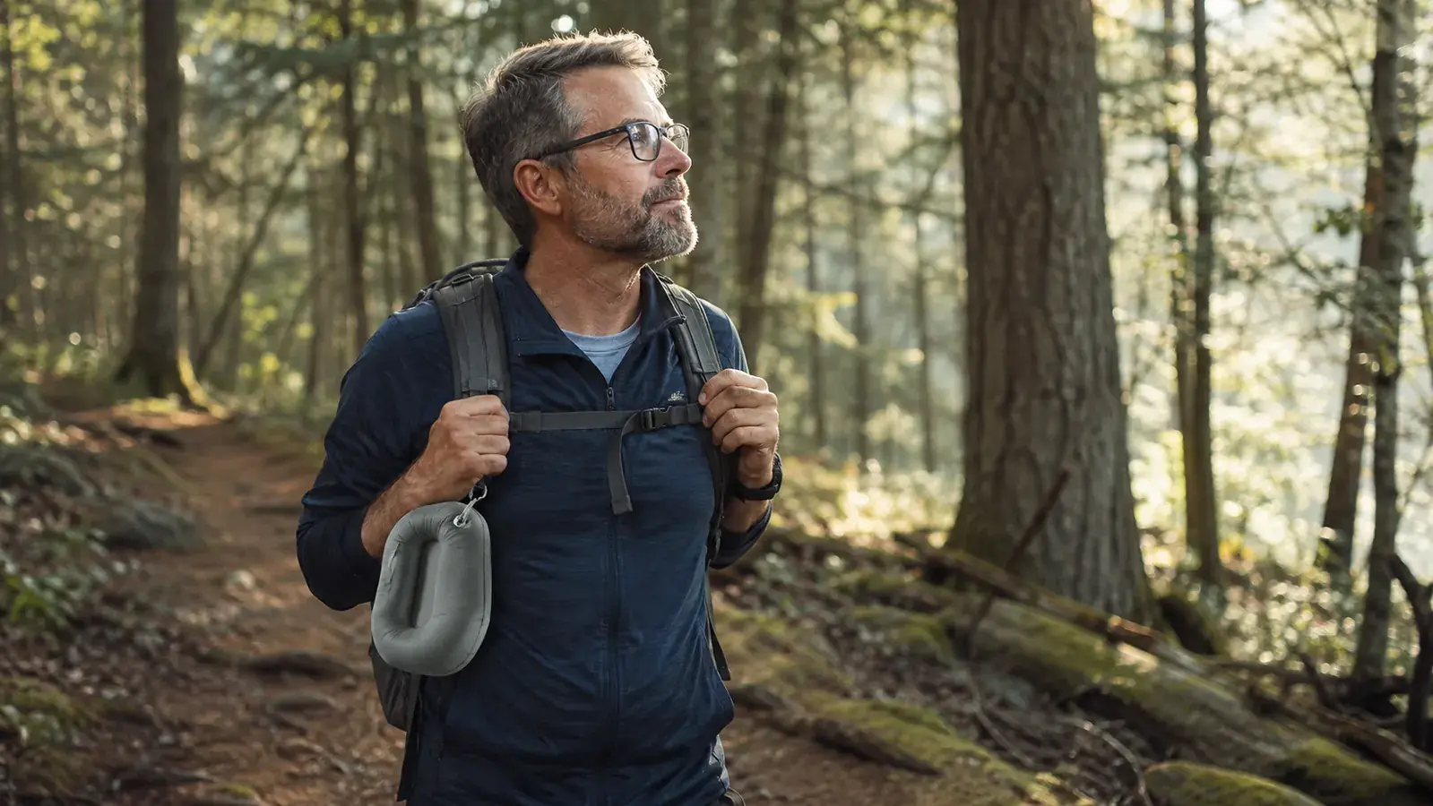 Hiker with a small daypack and a deflated inflatable pillow clipped to the outside strap